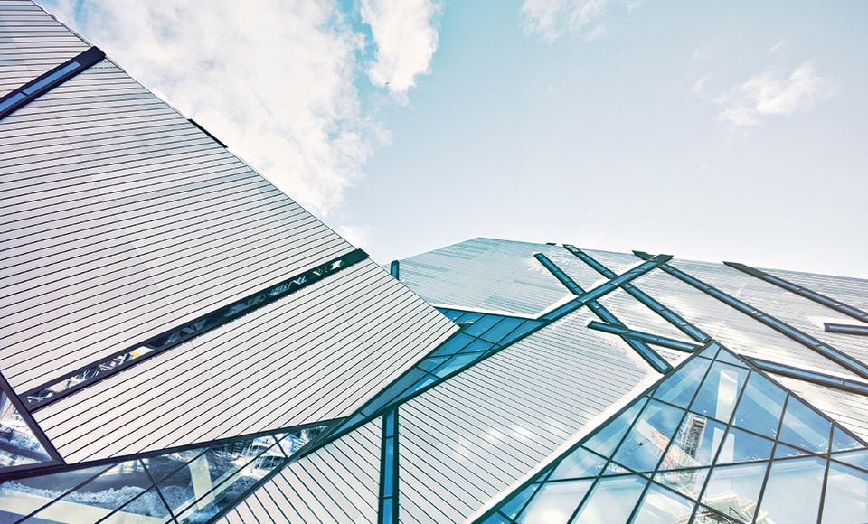 Abstract architectural forms of a modern building with reflective glass panels against a blue sky.